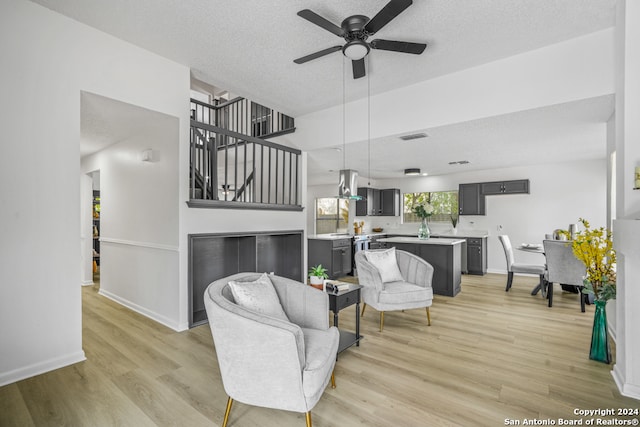 living room with light hardwood / wood-style floors, a textured ceiling, and ceiling fan