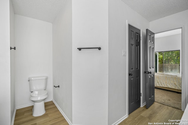 bathroom featuring toilet, a textured ceiling, and wood-type flooring