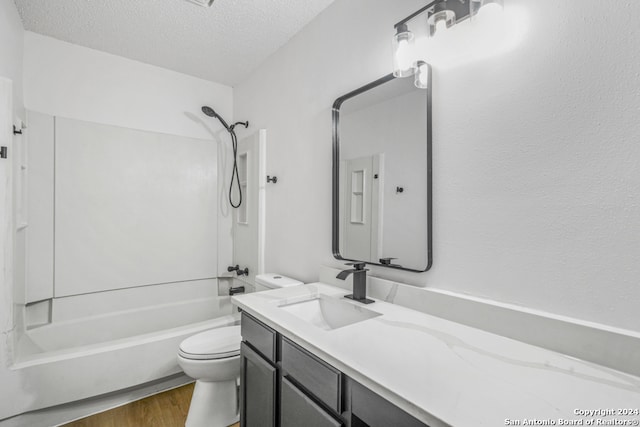 full bathroom with vanity, washtub / shower combination, a textured ceiling, and toilet