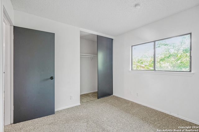 unfurnished bedroom with a closet, carpet, and a textured ceiling