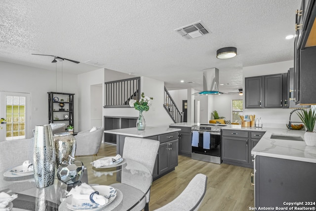 kitchen with a center island, stainless steel range with electric cooktop, gray cabinets, a textured ceiling, and light hardwood / wood-style floors