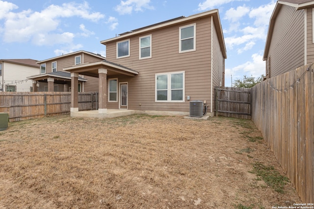 rear view of house featuring central air condition unit, a patio, and a lawn