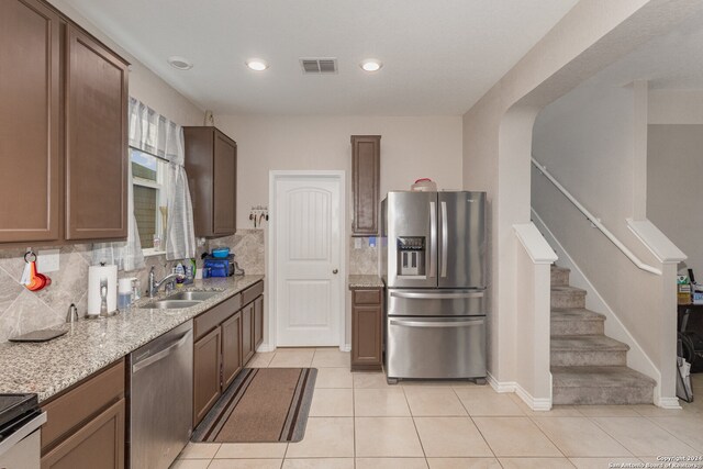 kitchen featuring backsplash, appliances with stainless steel finishes, sink, and light tile patterned floors