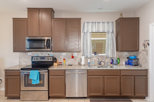 kitchen with sink, decorative backsplash, stainless steel appliances, and light tile patterned floors