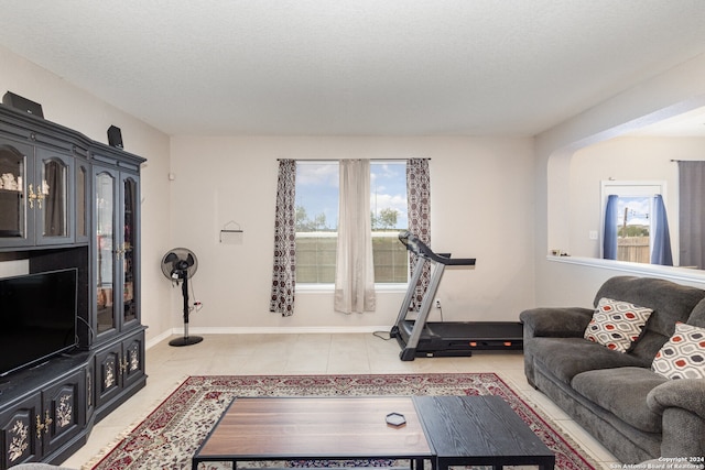 living room featuring a textured ceiling, light tile patterned floors, and plenty of natural light