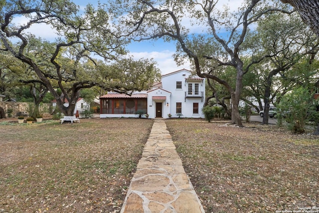 mediterranean / spanish home featuring a front lawn and a sunroom