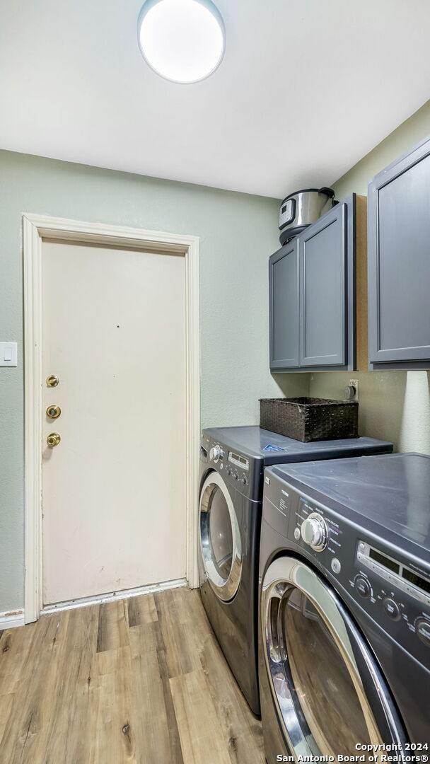 laundry area with cabinets, separate washer and dryer, and light wood-type flooring