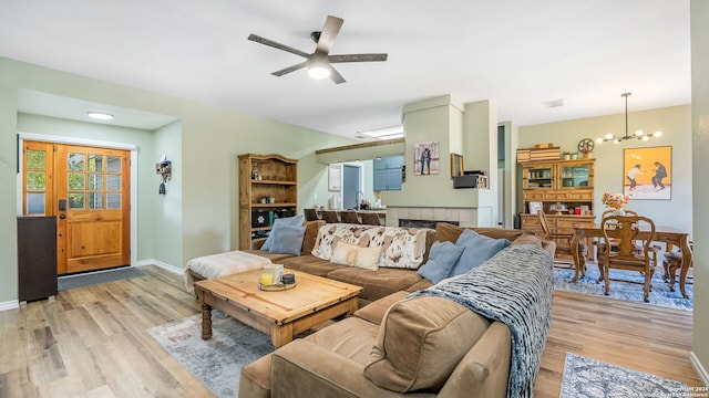 living room with ceiling fan with notable chandelier and light hardwood / wood-style flooring