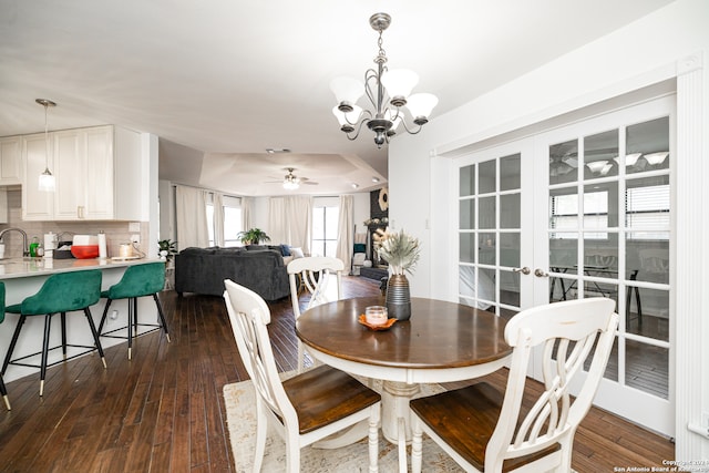 dining space with ceiling fan with notable chandelier and dark wood-type flooring