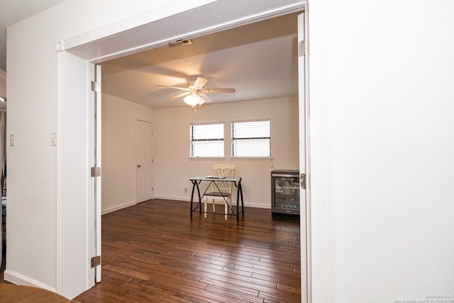 empty room featuring ceiling fan, dark wood-type flooring, and beverage cooler