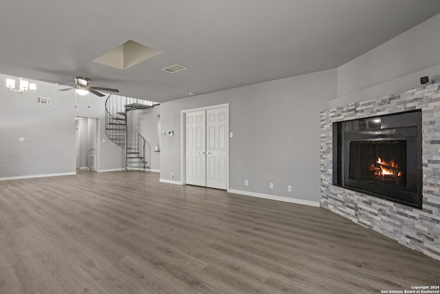 unfurnished living room featuring dark wood-type flooring, ceiling fan, and a stone fireplace