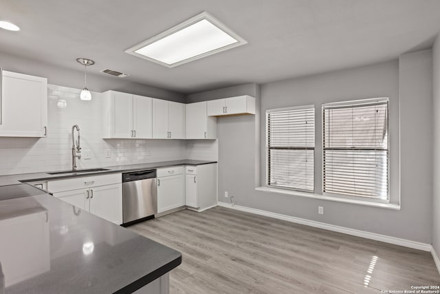 kitchen featuring stainless steel dishwasher, sink, white cabinets, and hanging light fixtures