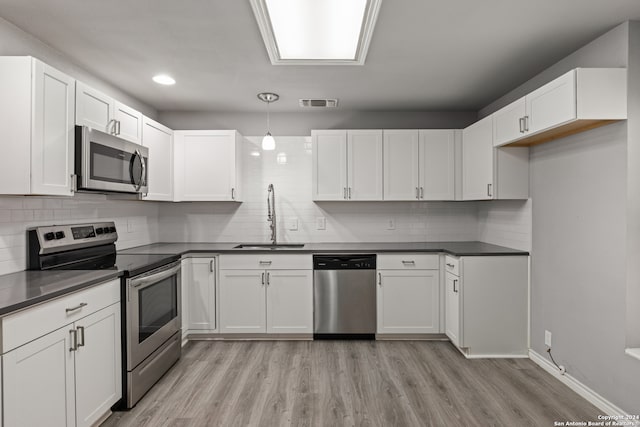 kitchen featuring appliances with stainless steel finishes, light hardwood / wood-style flooring, and white cabinetry