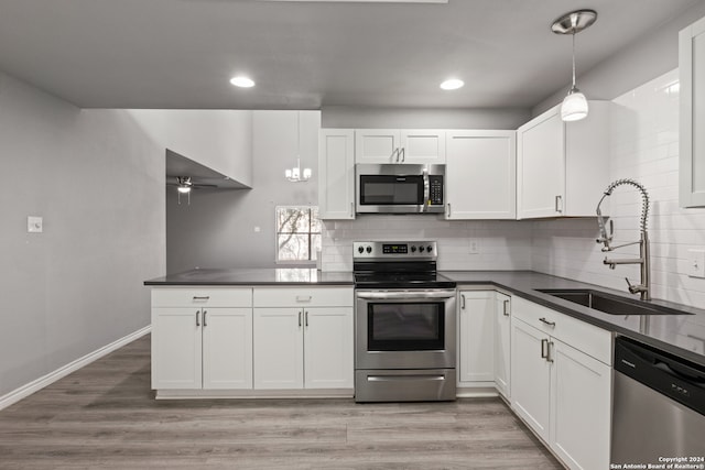 kitchen with sink, appliances with stainless steel finishes, hanging light fixtures, and white cabinetry