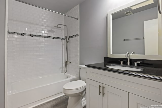 full bathroom featuring vanity, tiled shower / bath combo, hardwood / wood-style flooring, and toilet