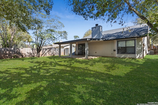 rear view of property featuring central air condition unit and a lawn