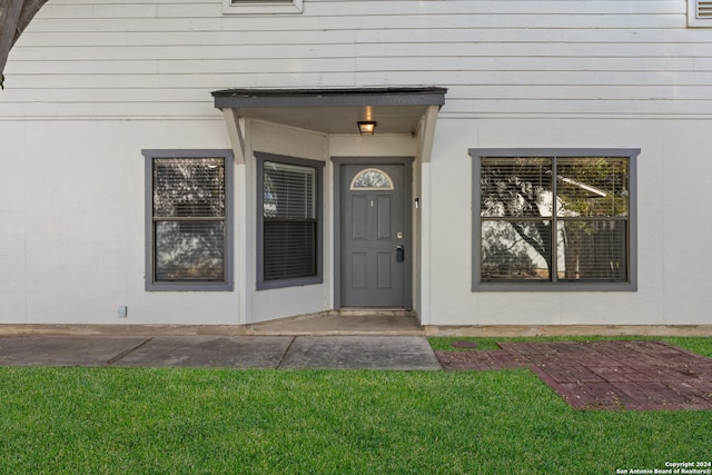 view of exterior entry with a lawn