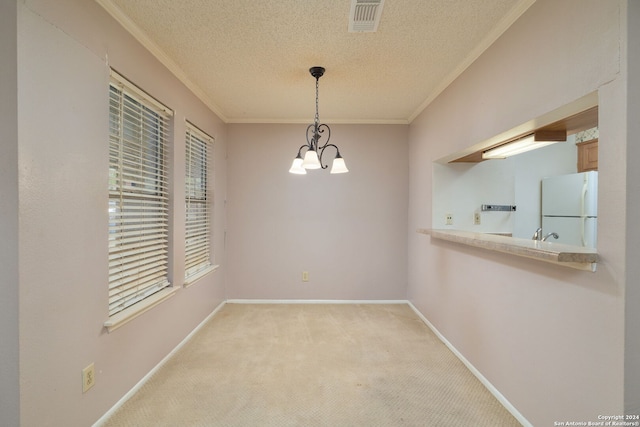 unfurnished dining area with crown molding, a notable chandelier, a textured ceiling, and light colored carpet