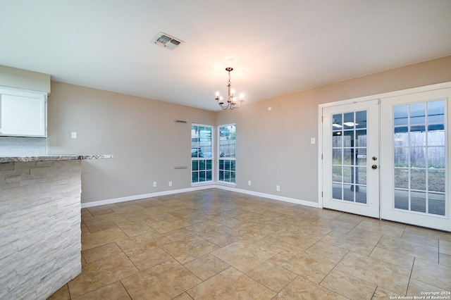 empty room with french doors and a chandelier