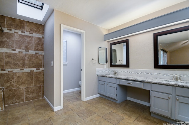 bathroom with toilet, vanity, and a skylight