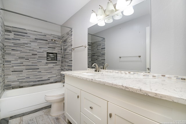 full bathroom featuring vanity, tiled shower / bath combo, wood-type flooring, and toilet