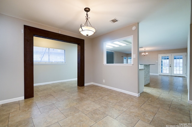 unfurnished room featuring an inviting chandelier and french doors