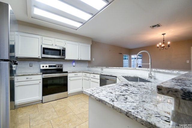 kitchen featuring white cabinets, appliances with stainless steel finishes, a chandelier, pendant lighting, and sink