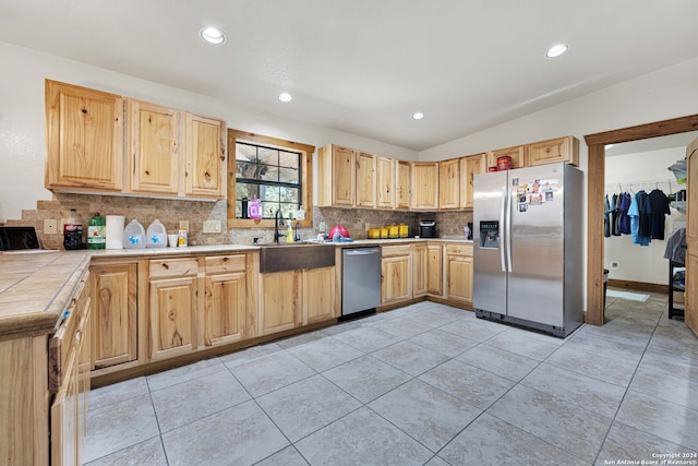 kitchen featuring light brown cabinets, backsplash, sink, light tile patterned flooring, and appliances with stainless steel finishes