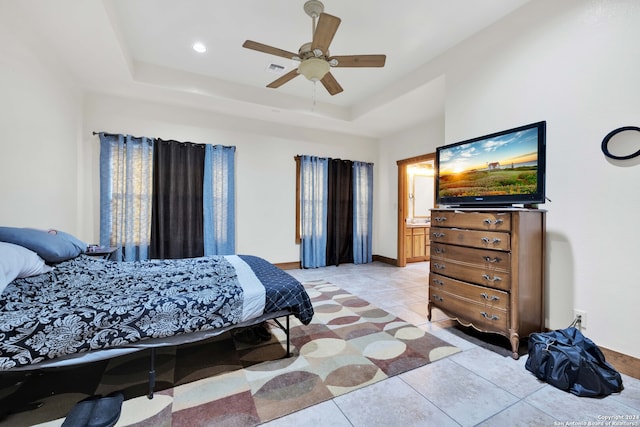 bedroom featuring ceiling fan, a raised ceiling, and light tile patterned flooring