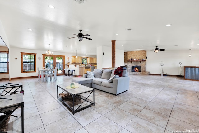 living room featuring light tile patterned flooring, a fireplace, and ceiling fan with notable chandelier