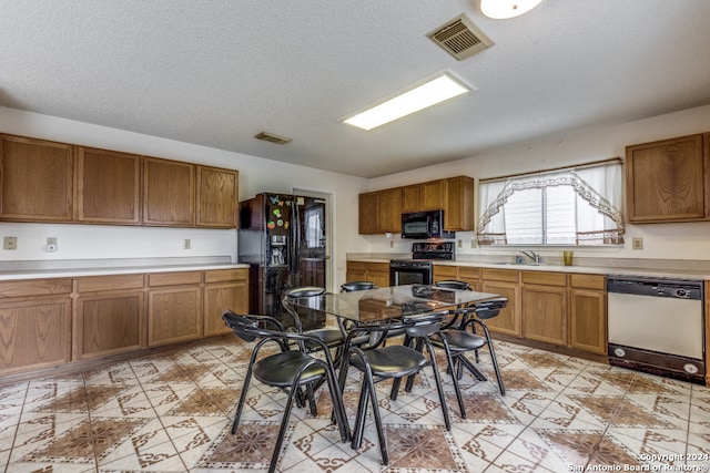 kitchen with a textured ceiling, black appliances, and sink