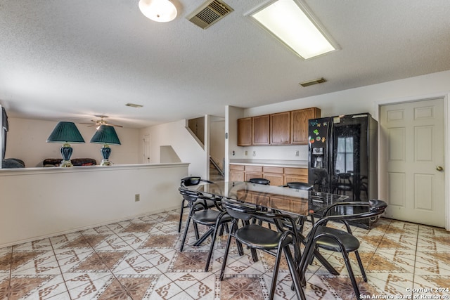 kitchen with ceiling fan, a textured ceiling, light tile patterned floors, and black fridge