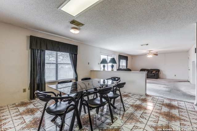 dining area with light carpet, a textured ceiling, and ceiling fan