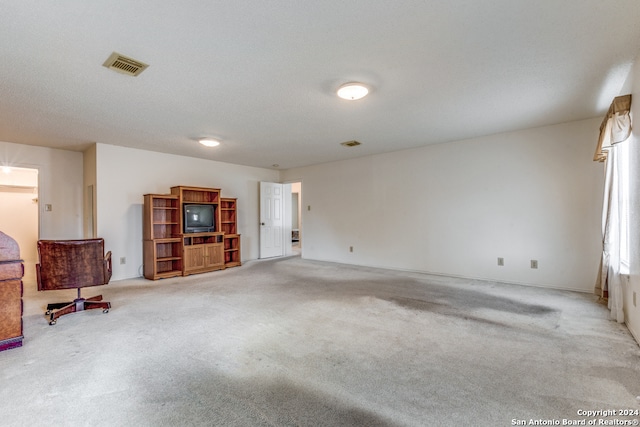 unfurnished living room with light carpet and a textured ceiling