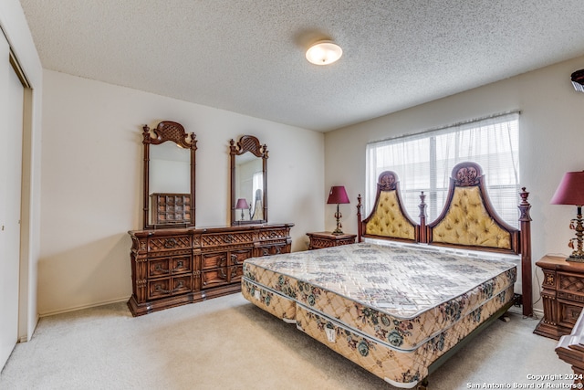 carpeted bedroom with a textured ceiling and a closet