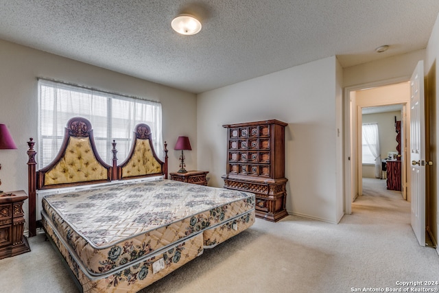 bedroom featuring a textured ceiling and light colored carpet