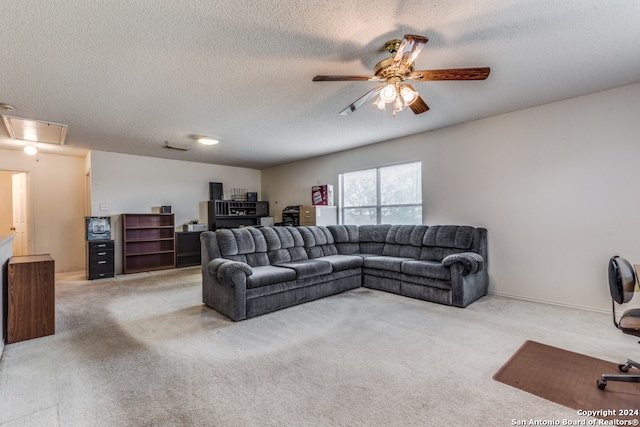 living room with ceiling fan, a textured ceiling, and light colored carpet