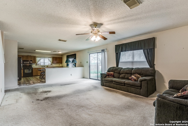 living room featuring ceiling fan, a textured ceiling, and carpet floors