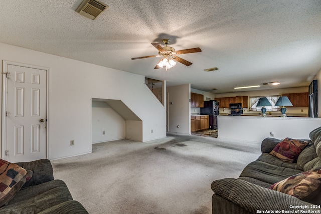 carpeted living room featuring ceiling fan and a textured ceiling