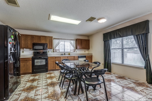 kitchen with a textured ceiling, black appliances, and sink