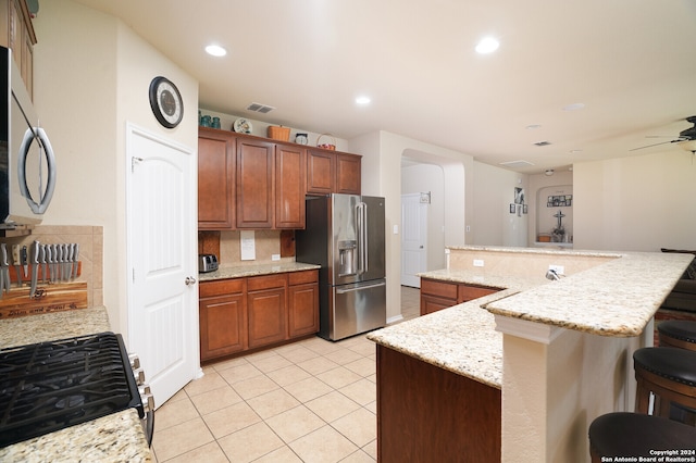 kitchen featuring a kitchen breakfast bar, a center island, stainless steel appliances, and light stone counters