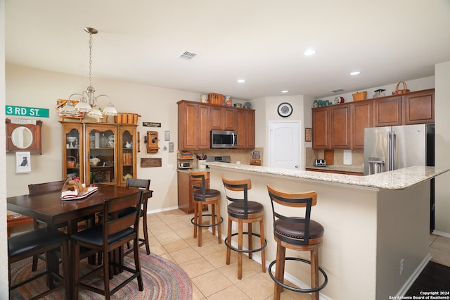 kitchen with decorative backsplash, a kitchen island, appliances with stainless steel finishes, a breakfast bar, and light stone countertops