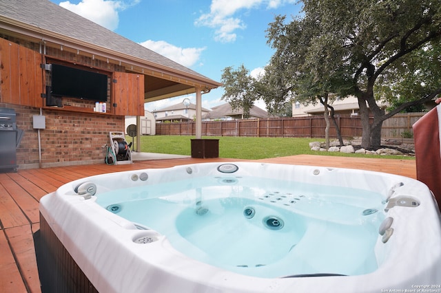 exterior space featuring a hot tub, a wooden deck, and a lawn