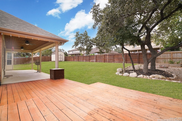 wooden deck featuring a storage unit, a yard, and ceiling fan