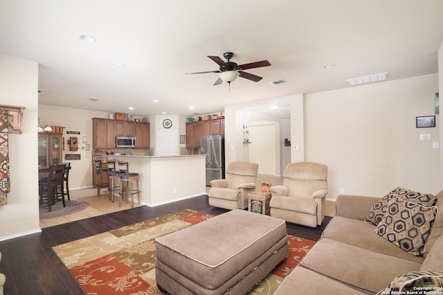 living room featuring ceiling fan and dark hardwood / wood-style flooring