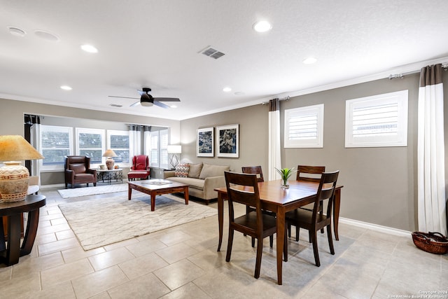 tiled dining space with ceiling fan and ornamental molding