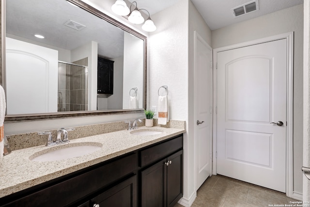 bathroom with a shower with door, tile patterned floors, and vanity