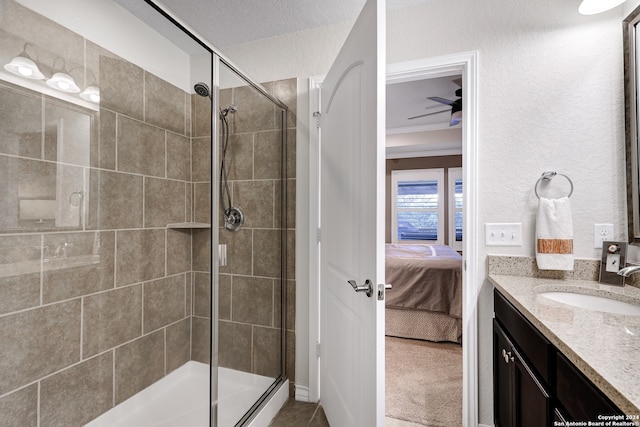 bathroom featuring vanity, a textured ceiling, ceiling fan, and a shower with door