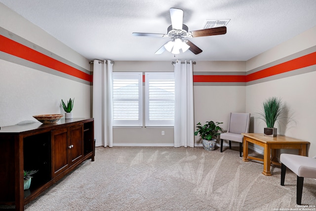 living area featuring ceiling fan, a textured ceiling, and light colored carpet