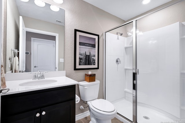 bathroom with vanity, toilet, and a shower with door